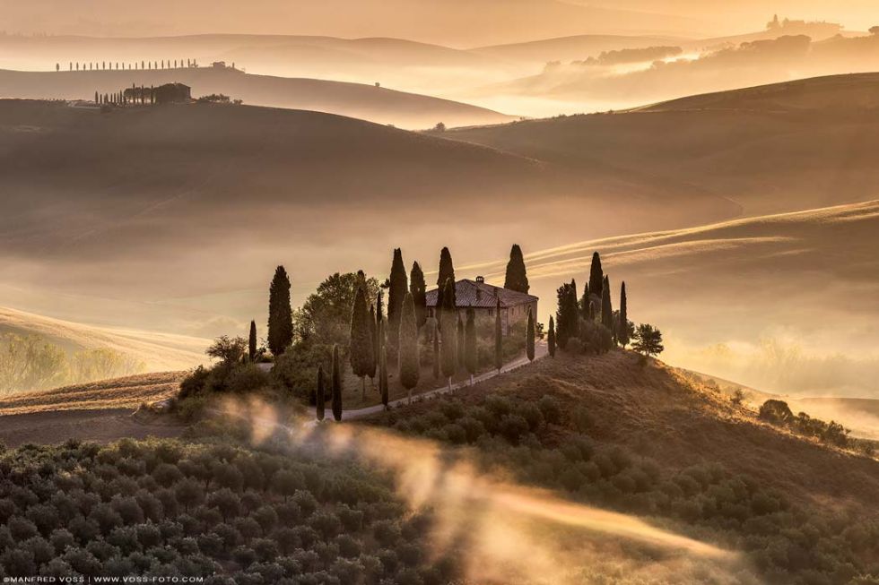 * Golden Amber *. Ein besonderer Morgen im Herzen der Toskana. Schöne Toskana Landschaft mit Wiesen Hügeln und Feldern mit lichtdurchflutetem Nebel bei einem stahlenden Sonnenaufgang.