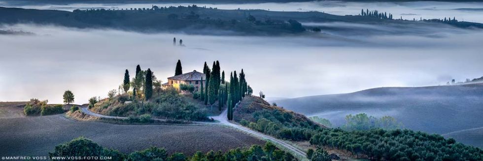 Stimmungsvolle Toskana Landschaft. In sanft geschwungenen Wellen zieht der Nebel morgens durh wisen Felder und Hügel. Harmonisch fürgt sich das Landhaus ein in die pittoresk toskanische Landschaft. Erdtöne. Toskana Italien im Oktober.