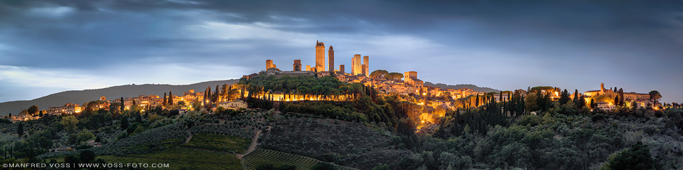 Landschaft in der Toskana mit der Stadt San Gimignano in Italien als weites Panorama zur blauen Stunde